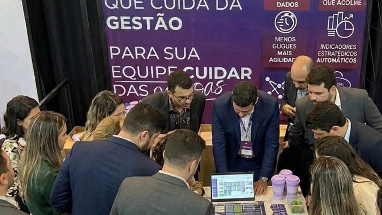 Profissionais do setor deathcare em estande tecnológico durante evento